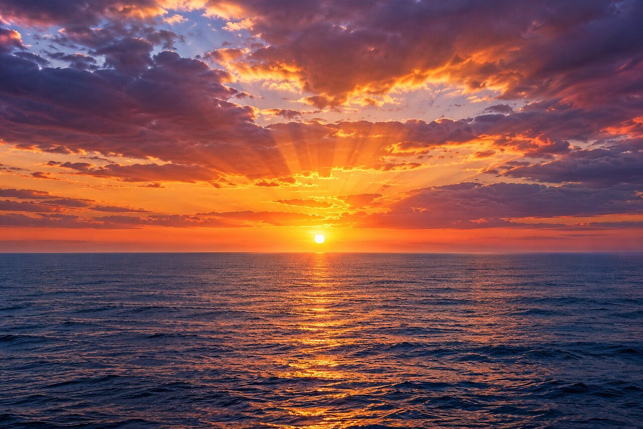 At sunrise the light fans out through gaps in the cloud on to the sea.